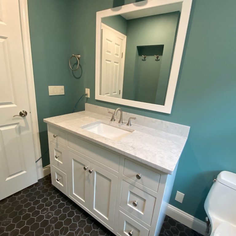 Completed blue bathroom viewed from the doorway with white vanity