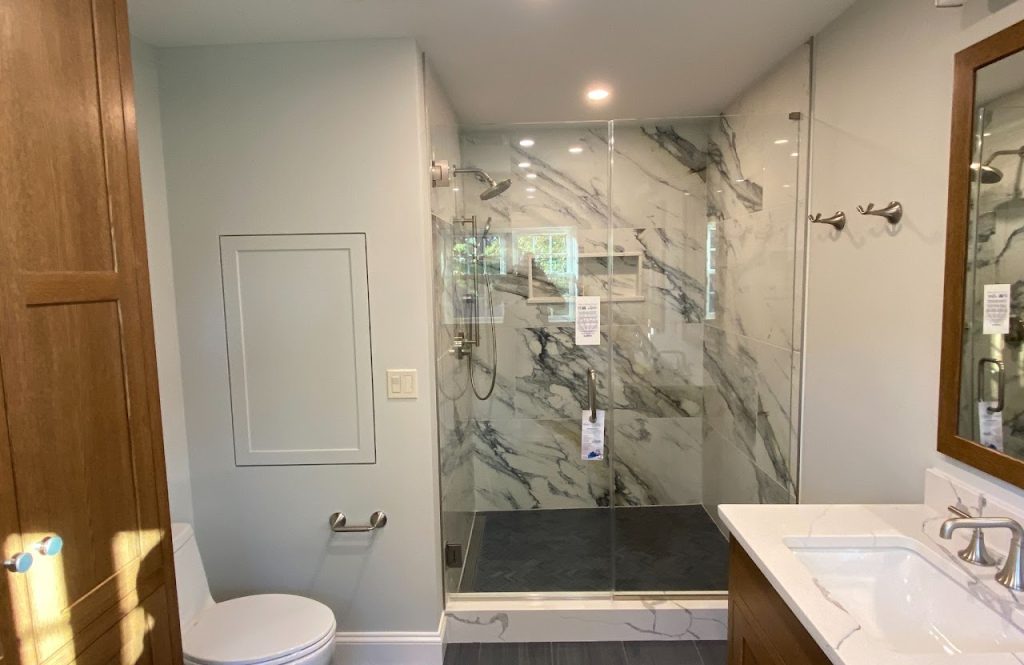Completed main bathroom with marble-look shower, wood cabinet and double vanity