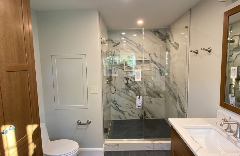 Completed main bathroom with marble-look shower, wood cabinet and double vanity