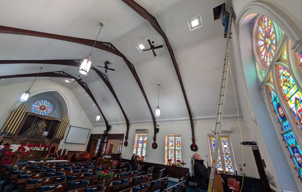 Existing church sanctuary viewed from the rear with stained glass and exposed roof beams