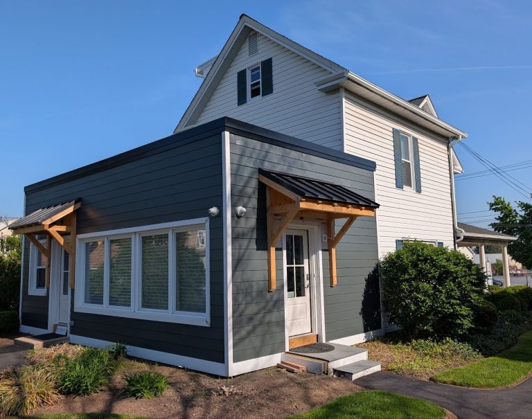 Completed office addition with dark siding and timber entrance canopy