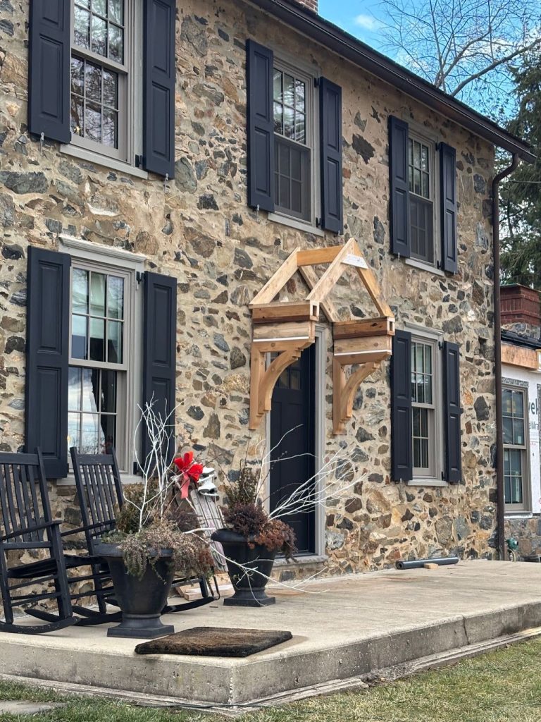 Existing stone farmhouse entrance with black shutters before the addition