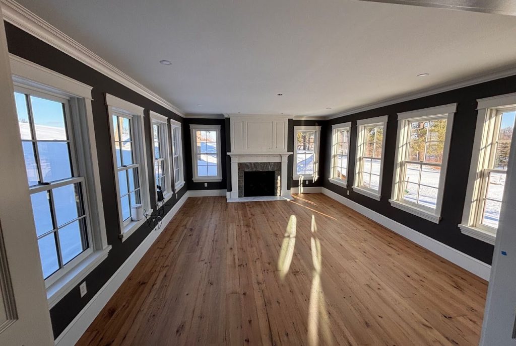 Completed sunroom interior with wood floor, fireplace and windows on three sides