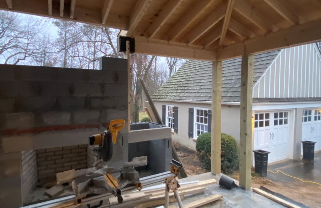 Covered deck framing with outdoor fireplace and grill area under construction