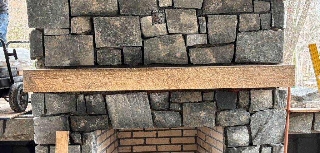 Stone veneer installation around the outdoor fireplace opening