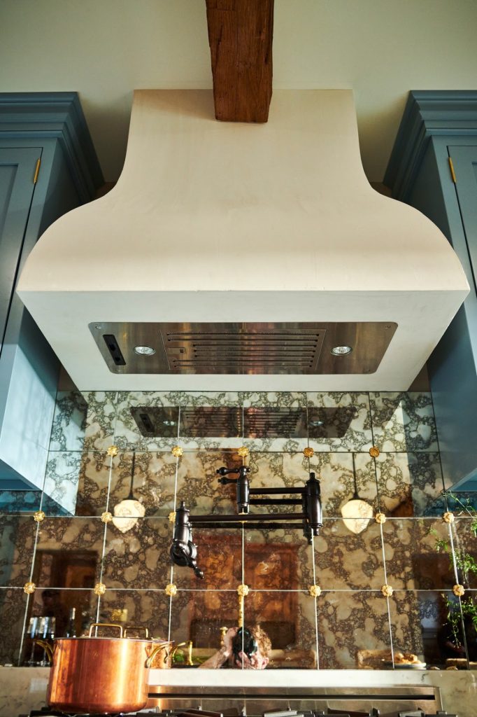 Close view of the custom range hood and reflective tile backsplash