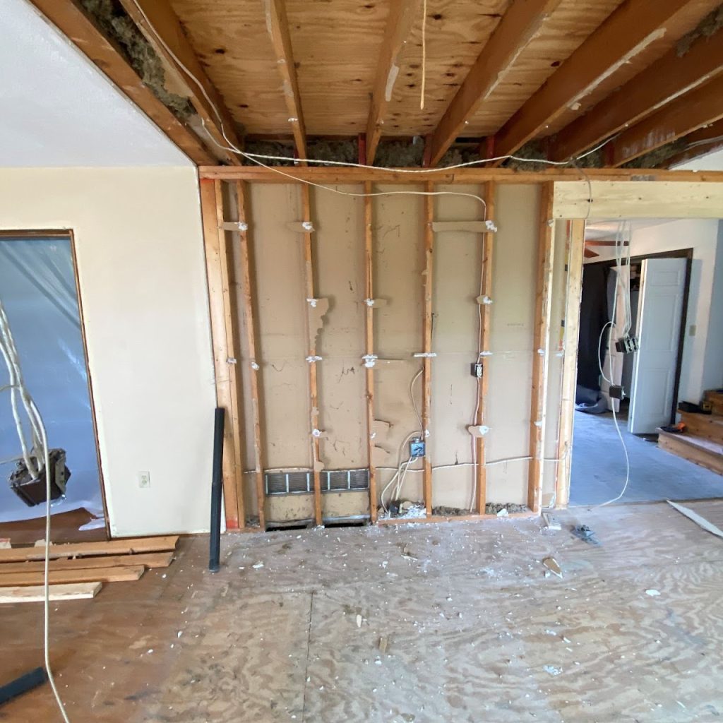 Kitchen demolition showing exposed wall studs, plumbing and open ceiling joists