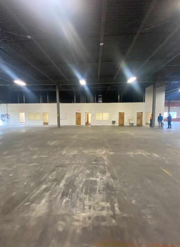 Existing warehouse interior with open concrete floor and high dark ceiling