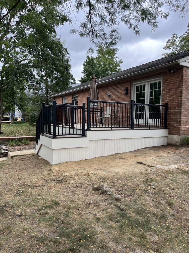 Completed raised rear porch with black railing viewed from the yard