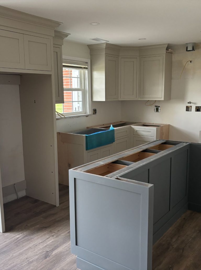 Kitchen renovation under construction with gray island and perimeter cabinets installed